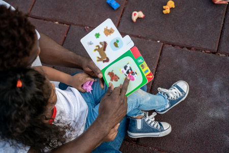 Young man and a little girl reading a book together and looking involvedの写真素材
