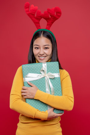 Dark-haired young woman in deer hat with a surprise box in handsの写真素材