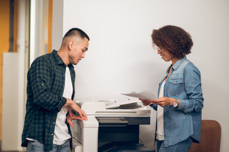 Assistant making document copies for her boss using the photocopierの写真素材