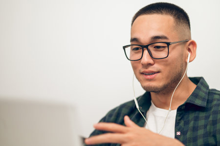 Freelancer communicating with someone via video call using earphonesの写真素材