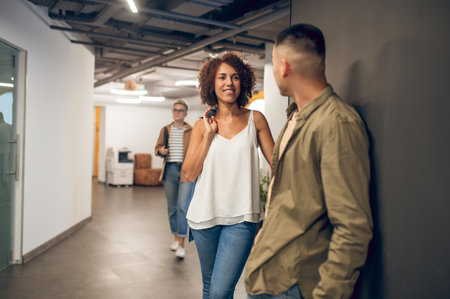 Company employee smiling at her coworker in the hallway