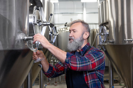 Brewery worker pouring fresh beer into the glassの写真素材
