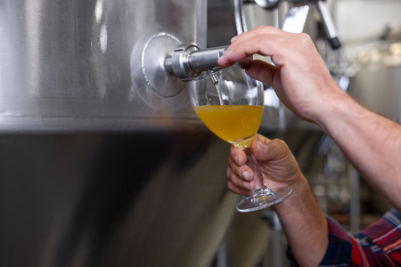 Brewery worker pouring fresh beer into the glassの写真素材