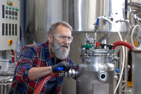 Mature man in protective eyeglasses working on a factory equipmentの写真素材