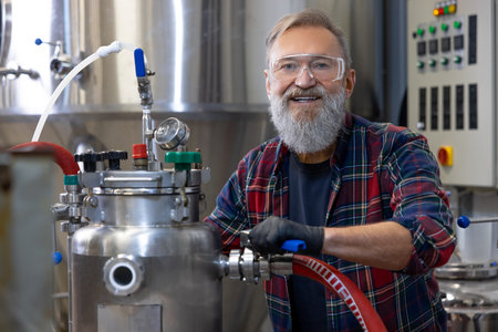 Mature man in protective eyeglasses working on a factory equipmentの写真素材