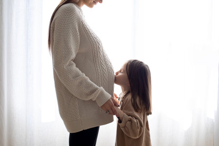 Little girl kissing her pregnant moms bellyの写真素材