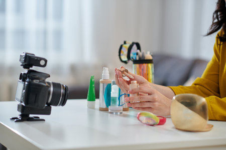 Woman sitting at the table and demonstrating beauty products onlineの写真素材