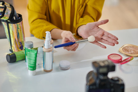Woman sitting at the table and demonstrating beauty products onlineの写真素材
