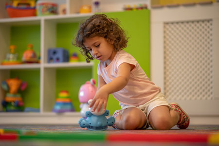 Cute little girl playing in a play room and looking interestedの写真素材