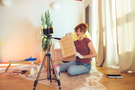 Cute ginger girl conducting an online tutorial on wood paintingの写真素材