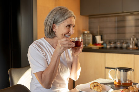 Gray-haired good-looking woman having tea in the morningの写真素材