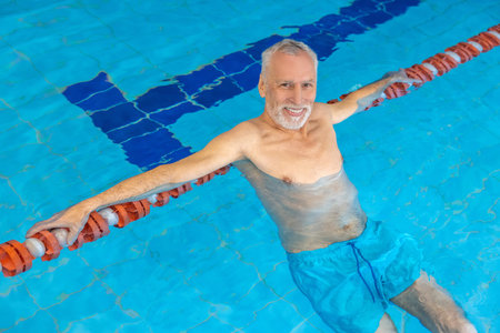 Gray-haired bearded swimmer looking contented at the swimming poolの写真素材