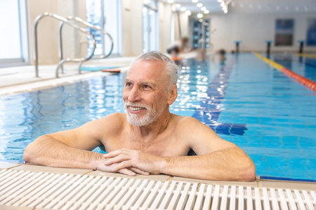 Gray-haired bearded swimmer looking contented at the swimming poolの写真素材