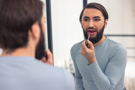 Attractive young man coloring his lips indoorsの写真素材