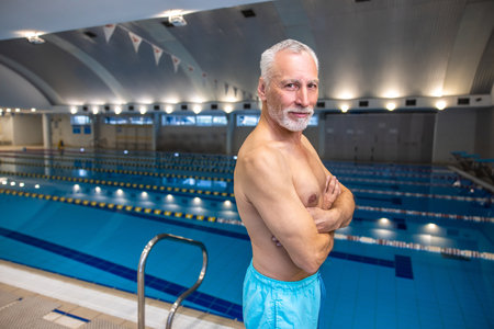 Good-looking fit senior man in blue swim shorts at the swimming poolの写真素材