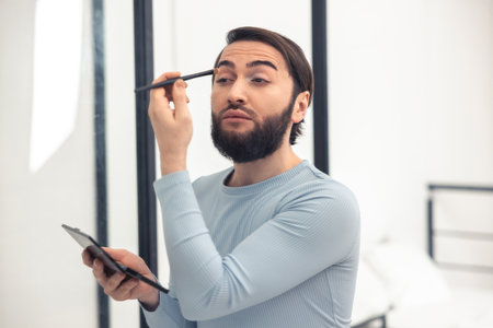 Transgender person applying the eyeshadows to his upper eyelidの写真素材