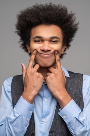 Dark-haired young man pretending to be happy