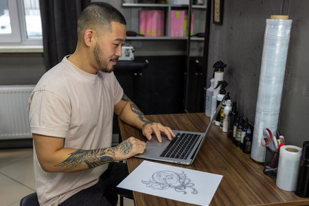 Young man with tattoos working on laptop
