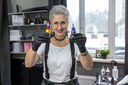 Female tattoo master holding bottles with tattoo inkの写真素材
