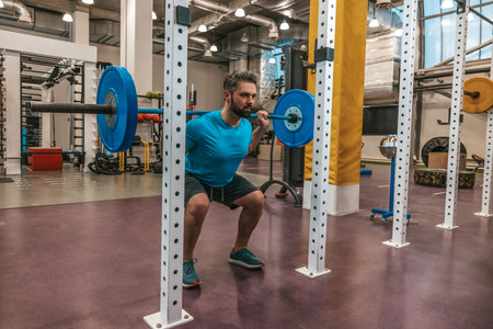 Athlete looking determined and serious while working with a bar-bellの写真素材