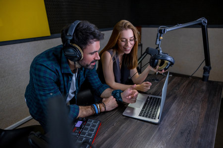 Two people sitting at the table and watching something on laptopの写真素材