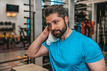 Young man wiping sweat with the towel after workoutの写真素材