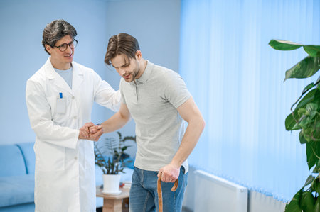 Nurse assisting a patient to walk with a stick