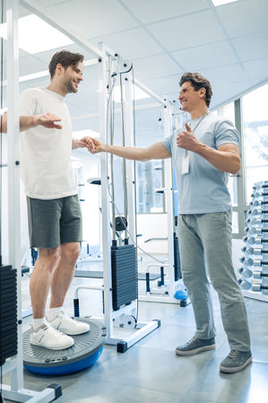 Doctor halping a patient to workout on a training deviceの写真素材