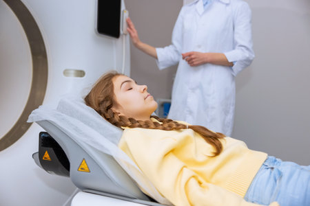 Little girl lying in mri scan machine unrecognizable radiographer pushing button on control panelの写真素材