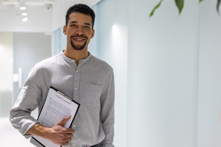 Smiling young office manager with documents looking ahead