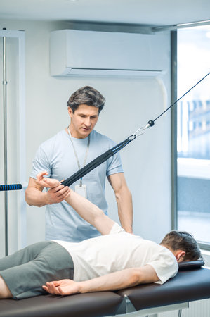 Male young patient having a session of arm hyperestension after trauma