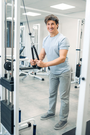 Smiling dark-haired man standing near training device