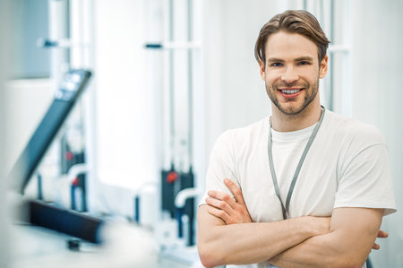 Young man in sportswear sitting on a training device in a gymの写真素材