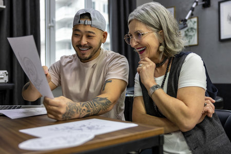 Grey-haired woman sitting with a tattoo masterの写真素材