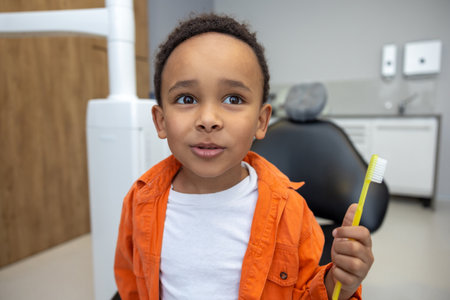 African-american boy looking involved while brushing his teethの写真素材