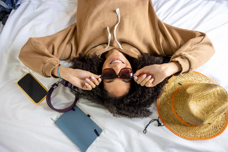 Young curly-haired woman getting ready for vacation and looking contented
