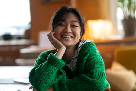 Asian girl in green shirt at home looking happyの写真素材