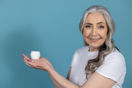 Woman in white tshirt demonstarting new anti-age cream and looking contented