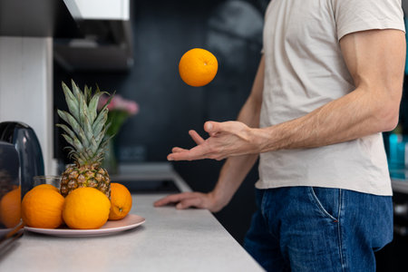 Man holding orange standing in kitchenの写真素材