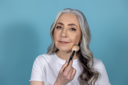Beautiful senior woman with face brushesの写真素材