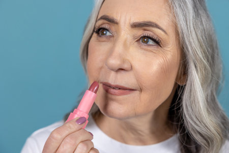 Beautiful aging woman with lipstick doing makeupの写真素材