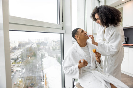 Young couple in bath robes having breakfast and having funの写真素材