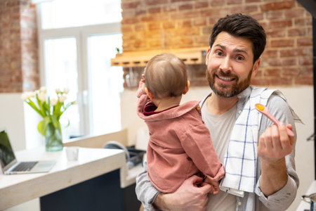 Father with baby girl feeding daughter with fruit or vegetable puree, complementary feeding of childの写真素材