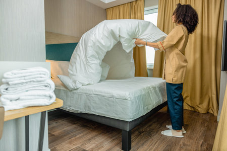 Young woman making bed in a hotel roomの写真素材