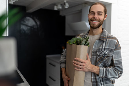 Man holding paper grocery shopping bag full of fresh healthy food vegetables in his hand.の写真素材