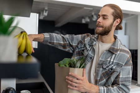 Man unpacking vegetables and fruits in kitchen after vising store, buying fresh products.の写真素材