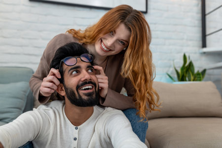 Married young couple sitting in room together, woman and man having fun, enjoying leisure time.の写真素材