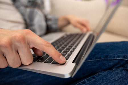Unrecognizable guy using laptop working online typing keyboard.