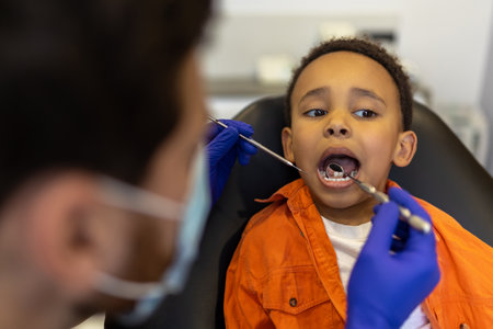 Scared little boy sitting with open mouth at the dentists chairの写真素材