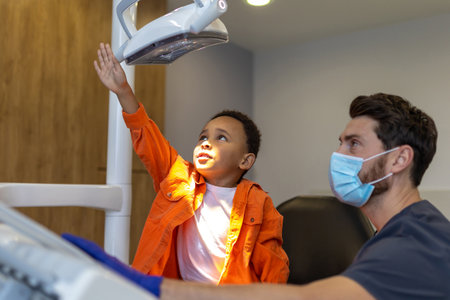 Dark-skinned boy loking interested in dental lampの写真素材